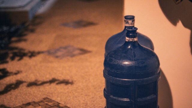 a blue bottle sitting on the floor next to a wall