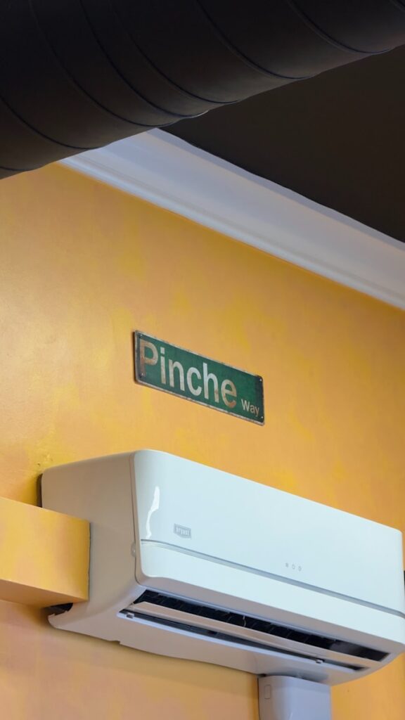 A white air conditioner mounted to a yellow wall